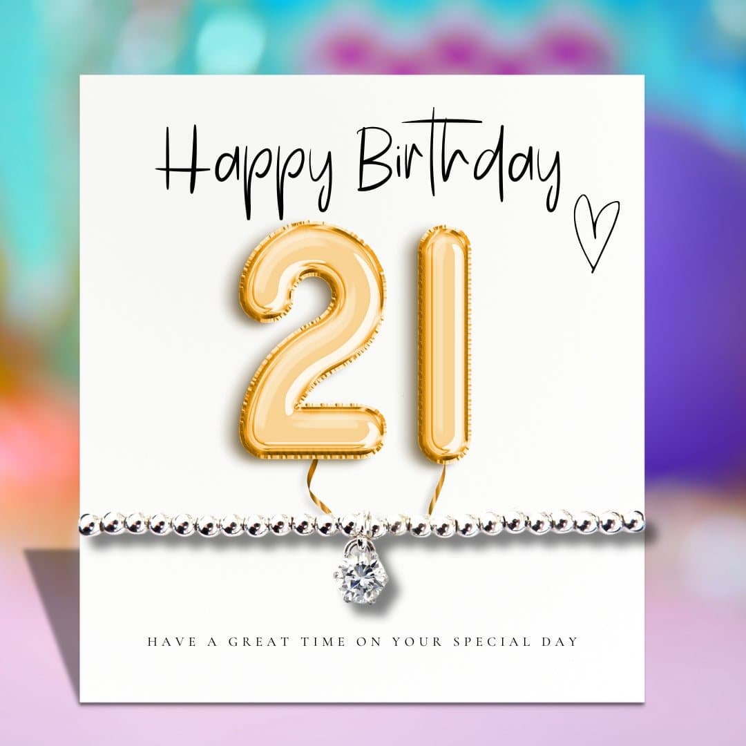Silver stretch beaded bracelet with a sparkly charm beside a gold balloons birthday card