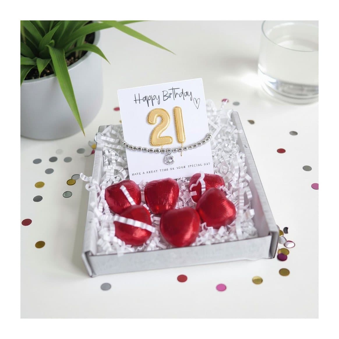 21st birthday gift box with a beaded bracelet, gold balloon card and chocolate hearts