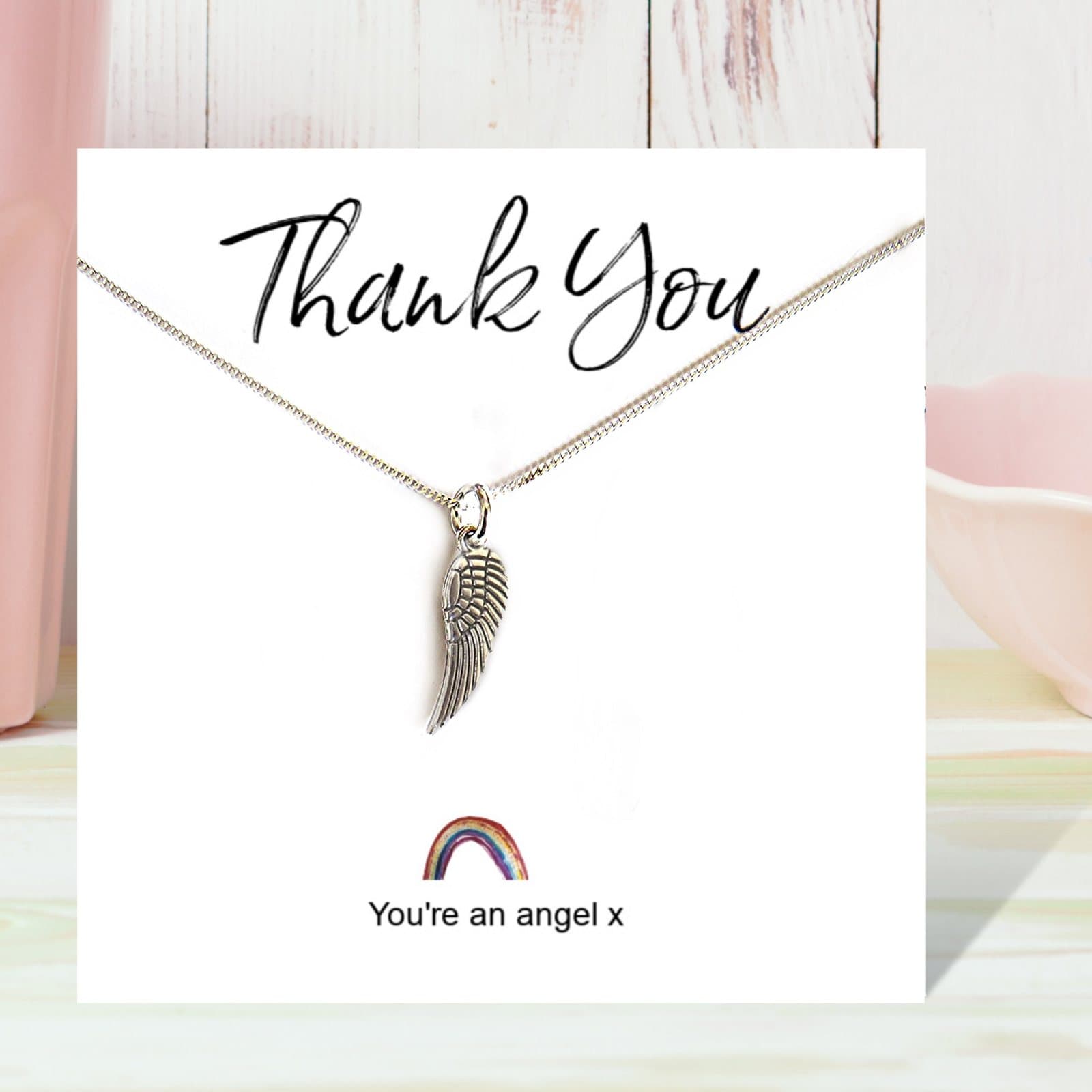 Angel wing necklace on a rainbow thank you card