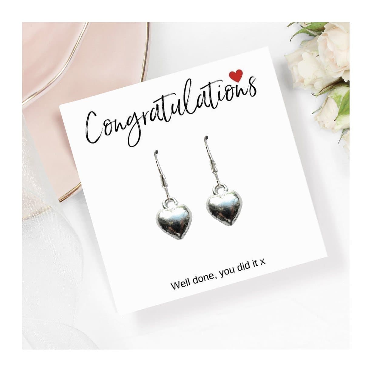 Silver heart charm earrings presented on a congratulations message card