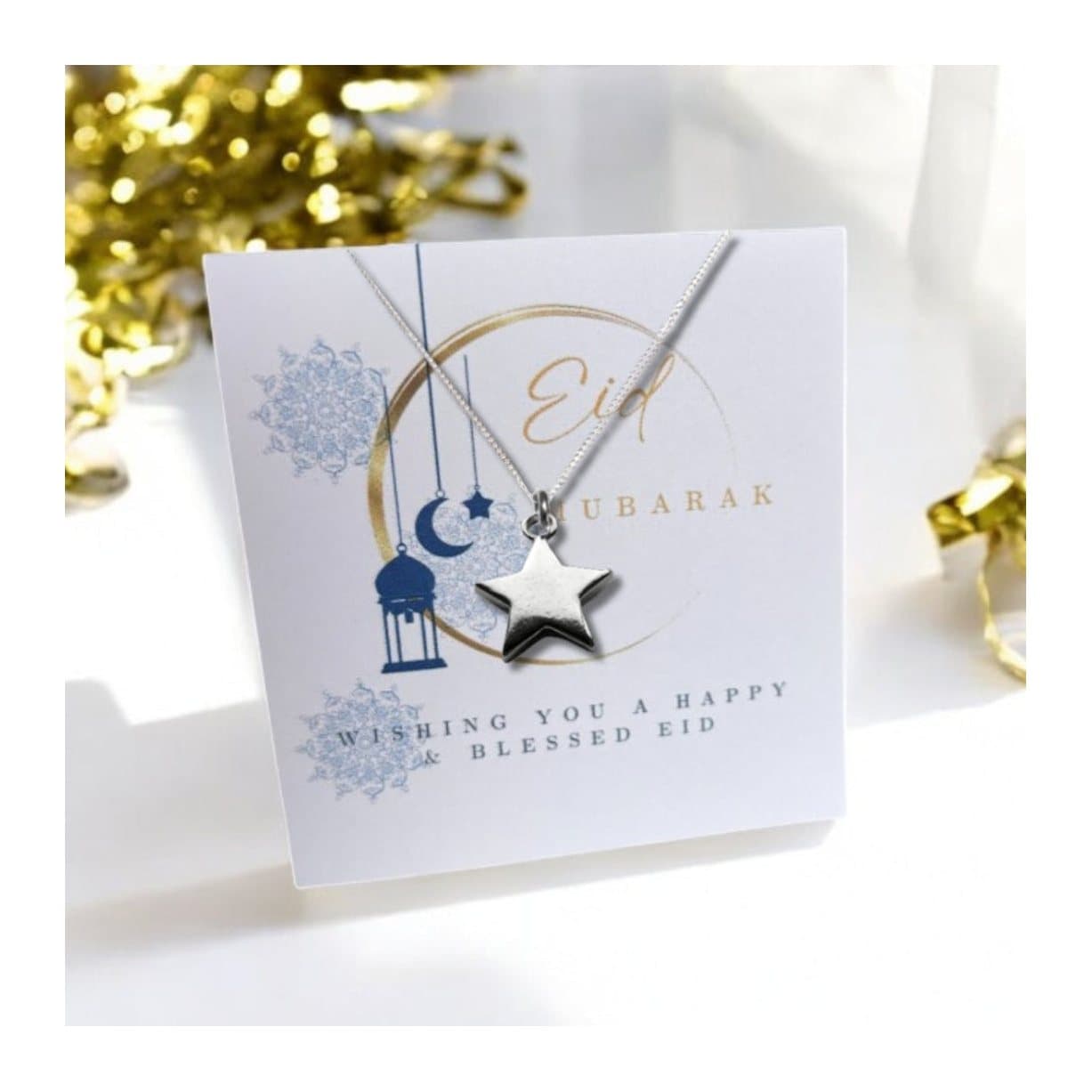 Silver star necklace presented on a card reading Eid Mubarak with a moon design