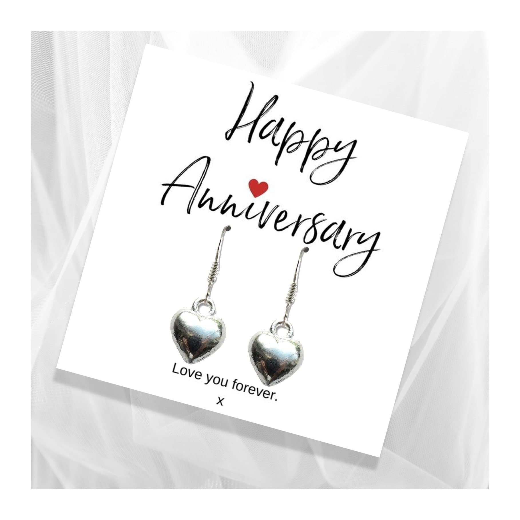Silver heart charm earrings beside a Happy Anniversary message card
