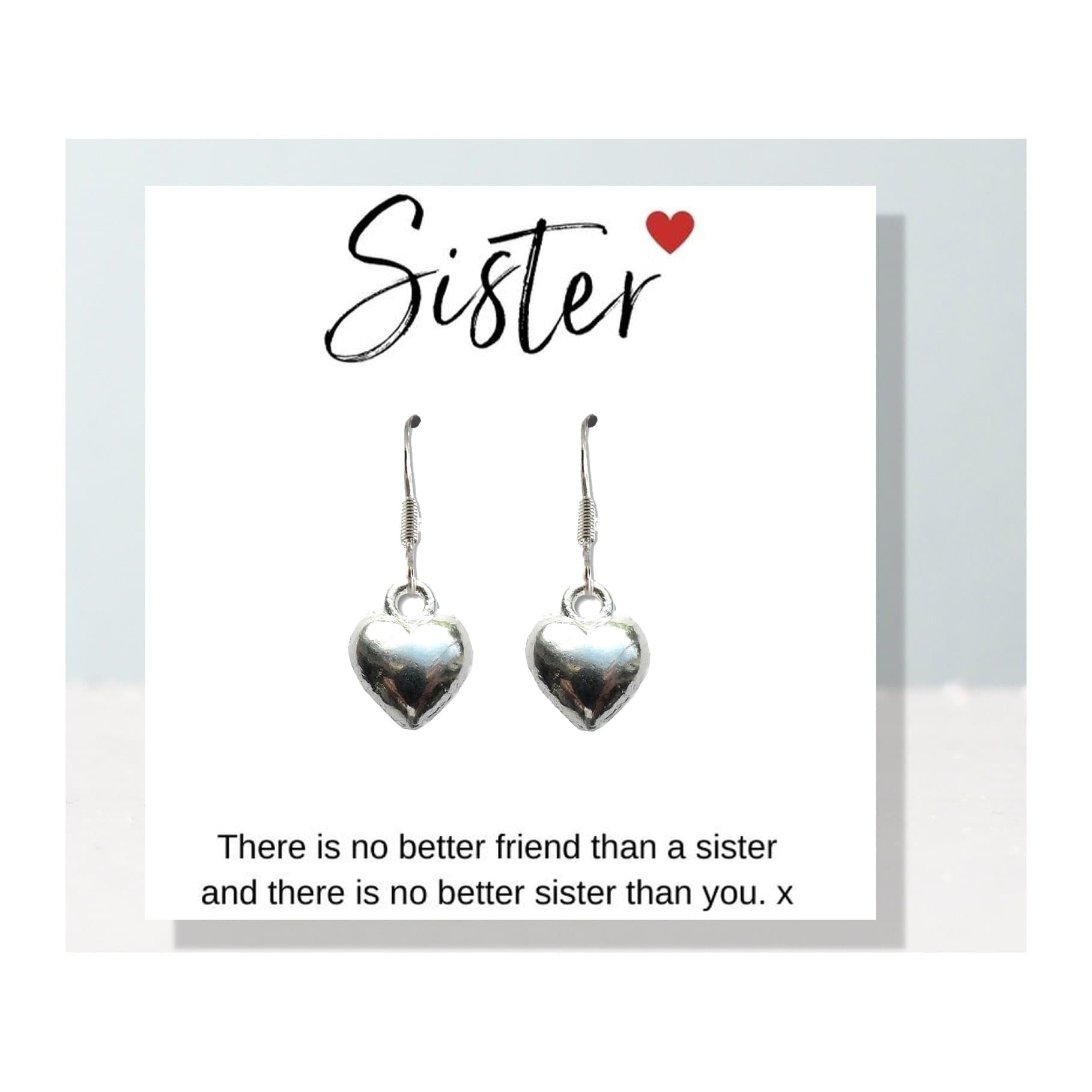 Silver heart earrings on a sister quote gift card beside a black gift box