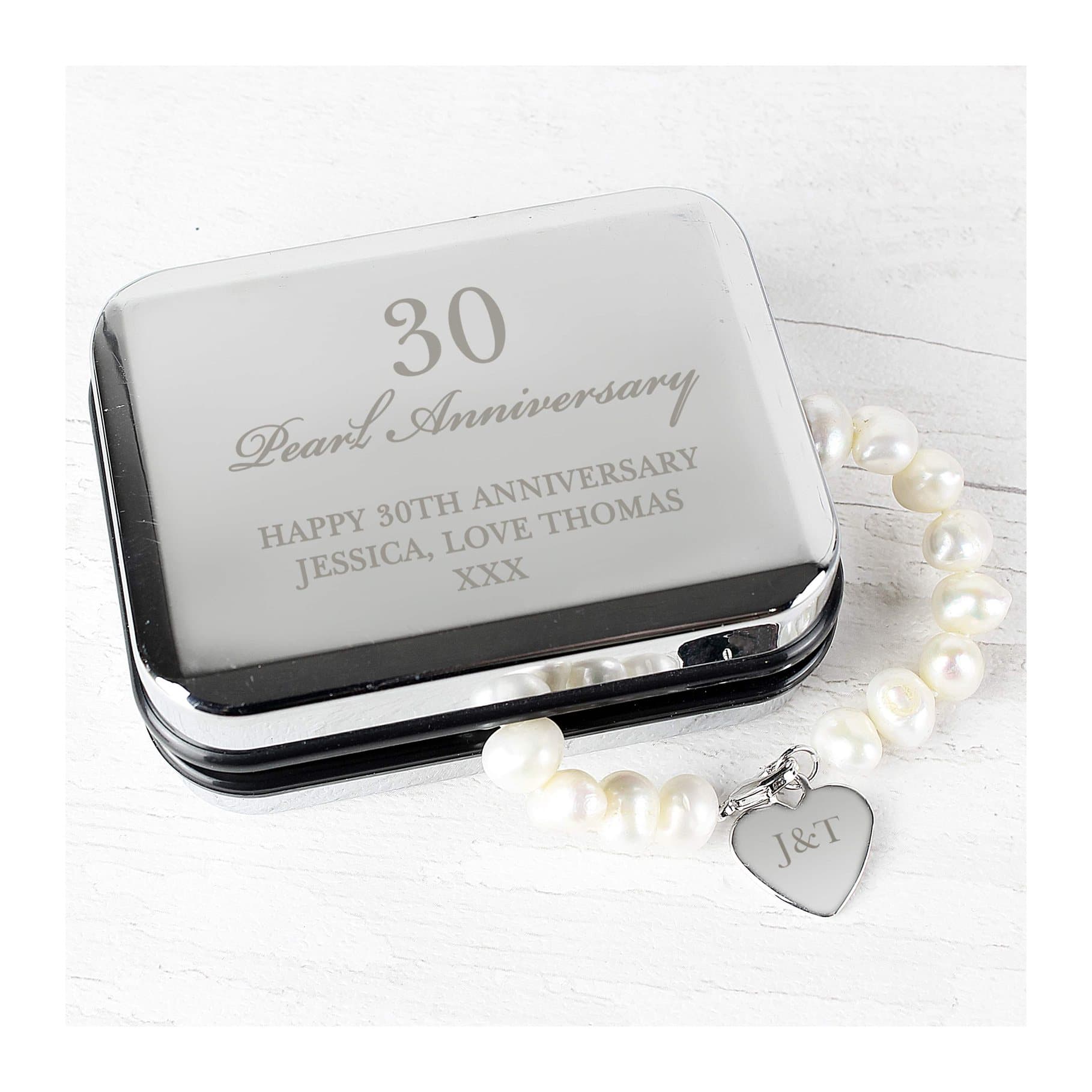 Pearl bracelet with a heart tag beside a personalised chrome gift box