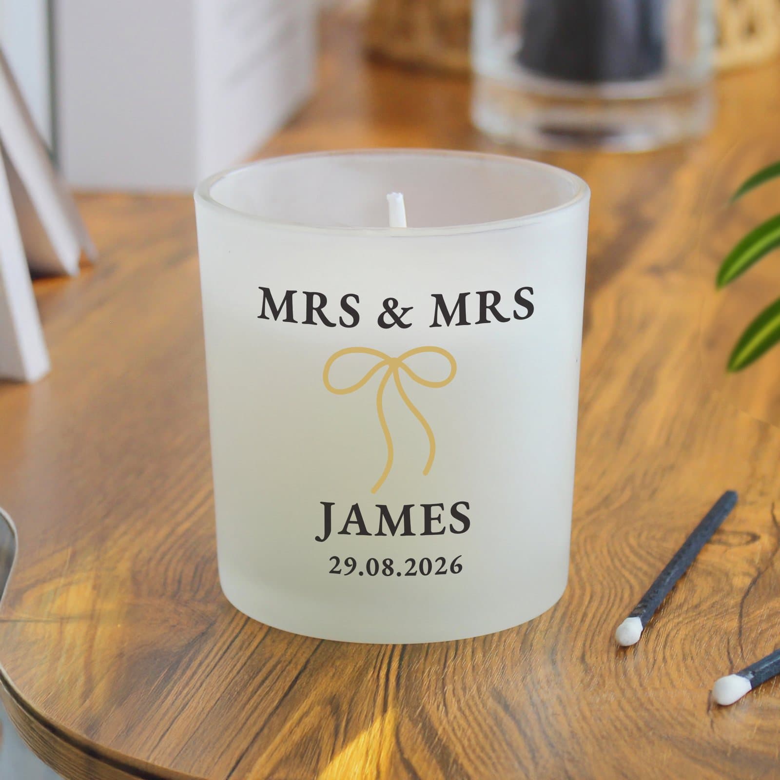 Frosted candle with a black and gold bow and personalised text