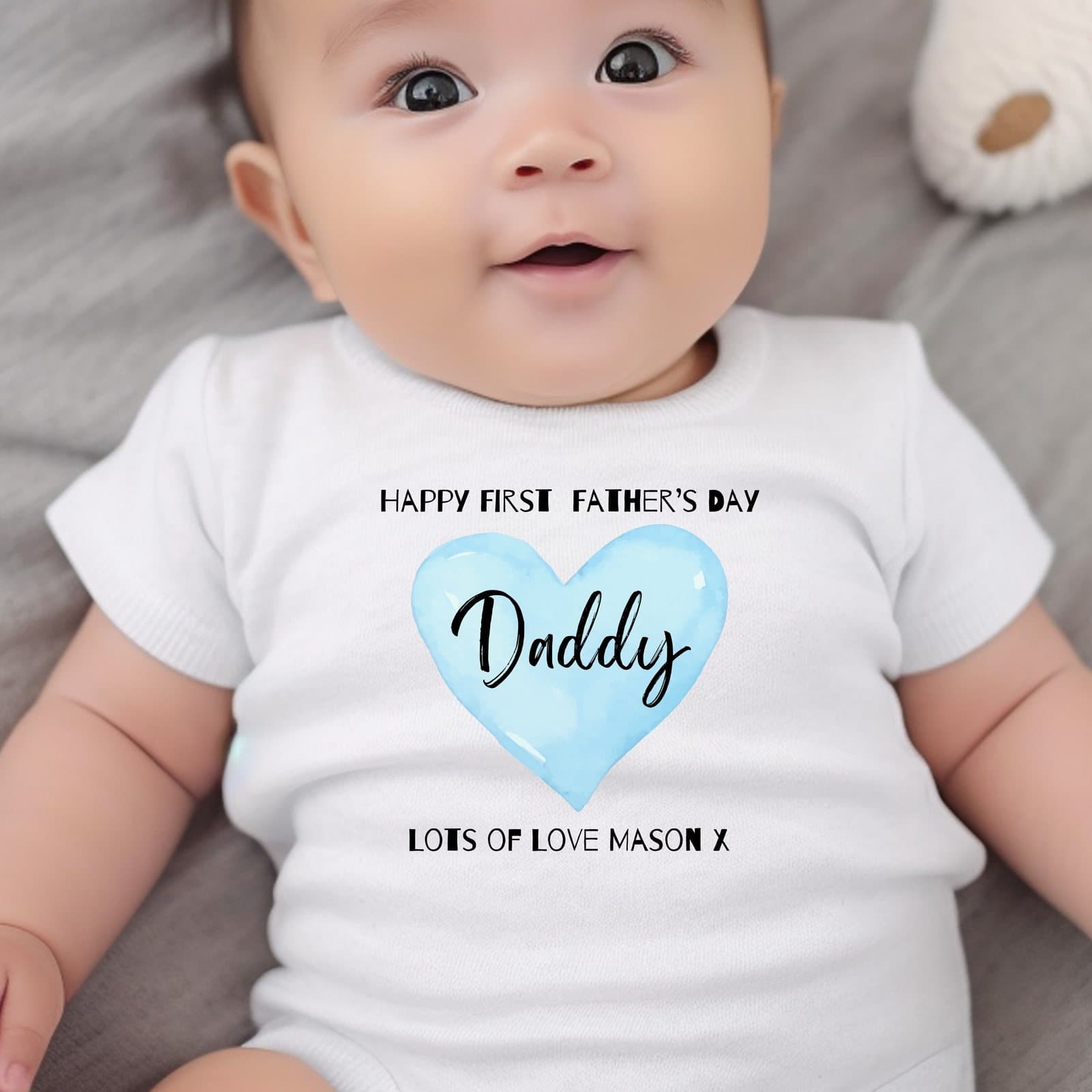 Blue baby babygrow with a heart design and the words Happy First Fathers Day