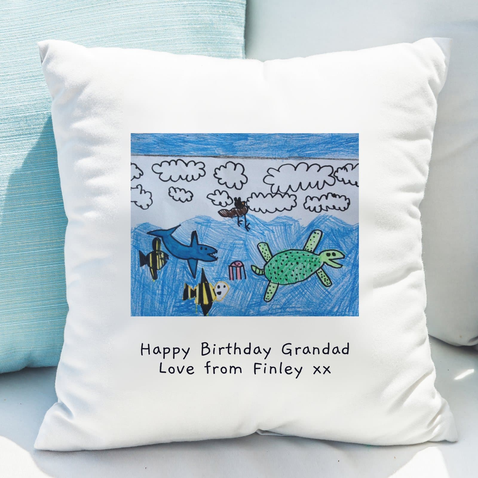 Square cushion printed with a child's drawing and two lines of text