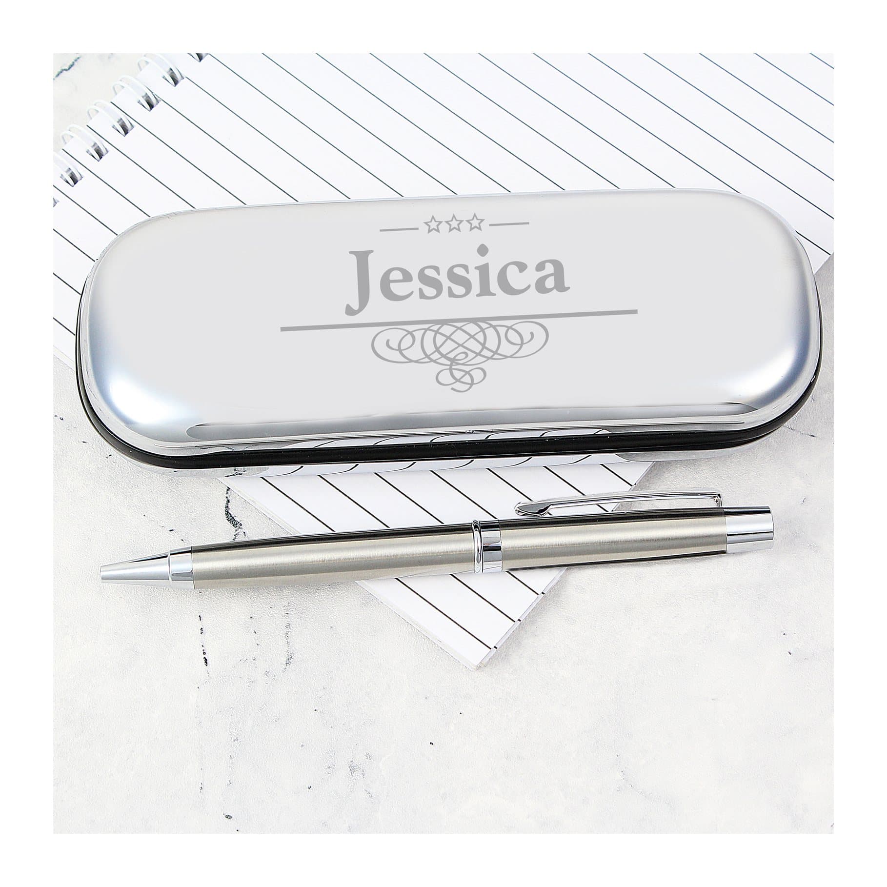 Chrome plated pen case engraved with a name beside a ball point pen