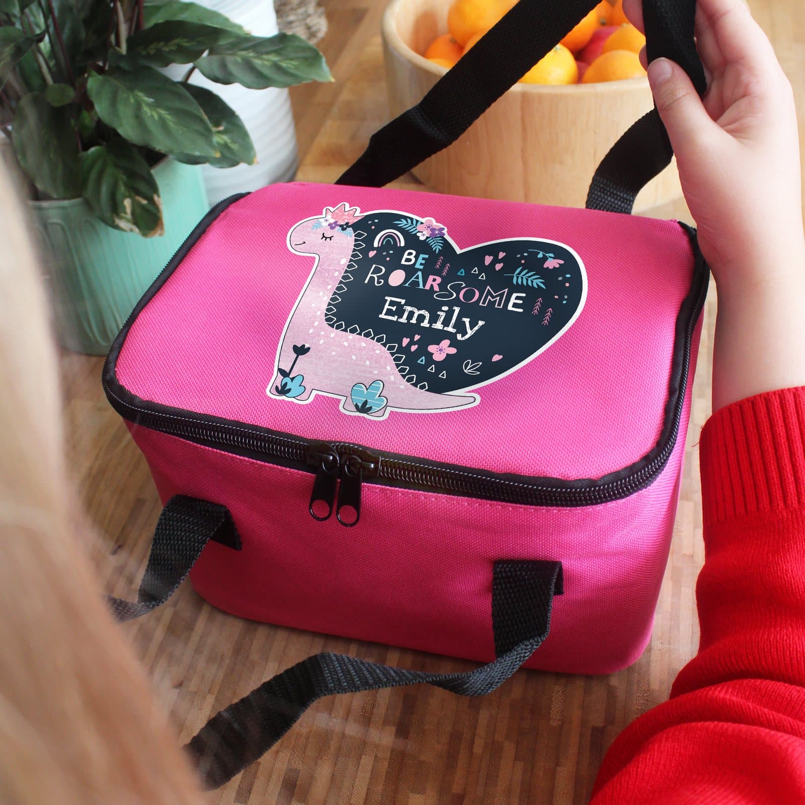 Pink dinosaur lunch bag with two carry straps and a personalised name