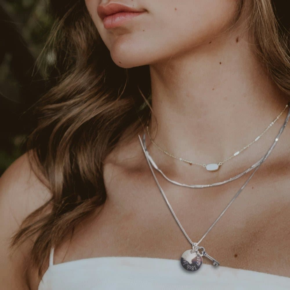 Silver key charm necklace with a round engraved charm on a chain