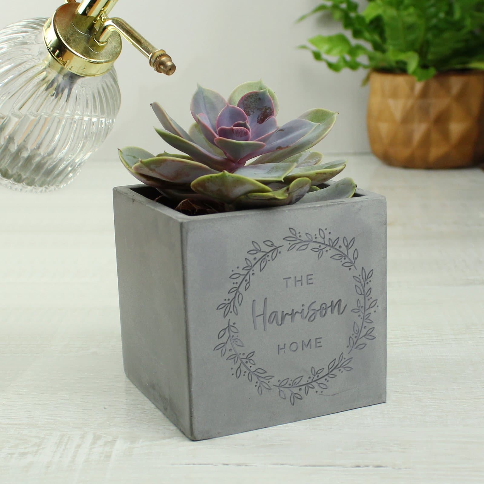 Concrete plant pot with a floral wreath design and three lines of text
