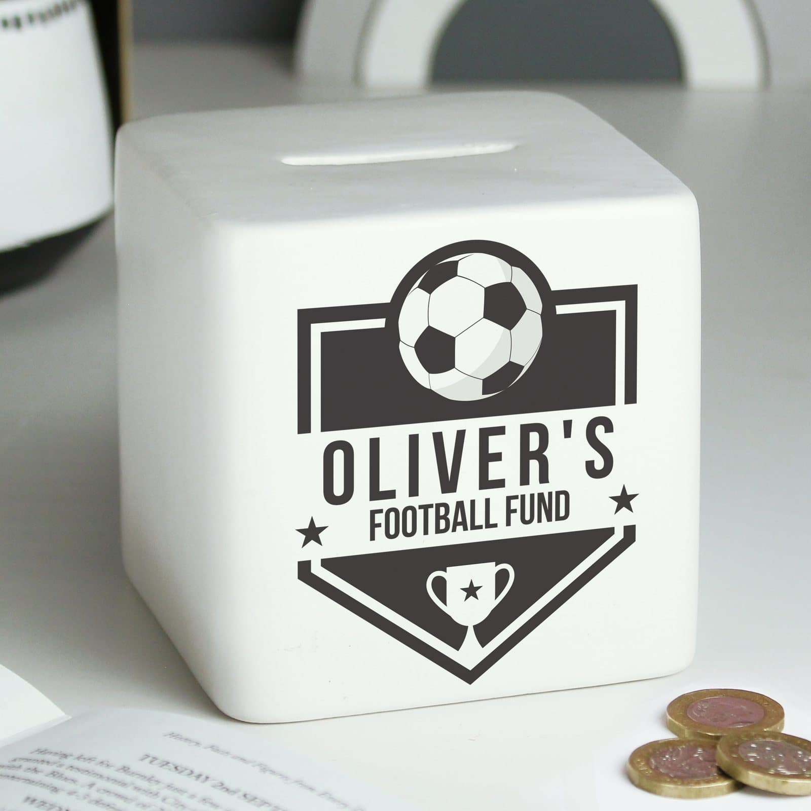 Square ceramic money box with a football badge design and two lines of text