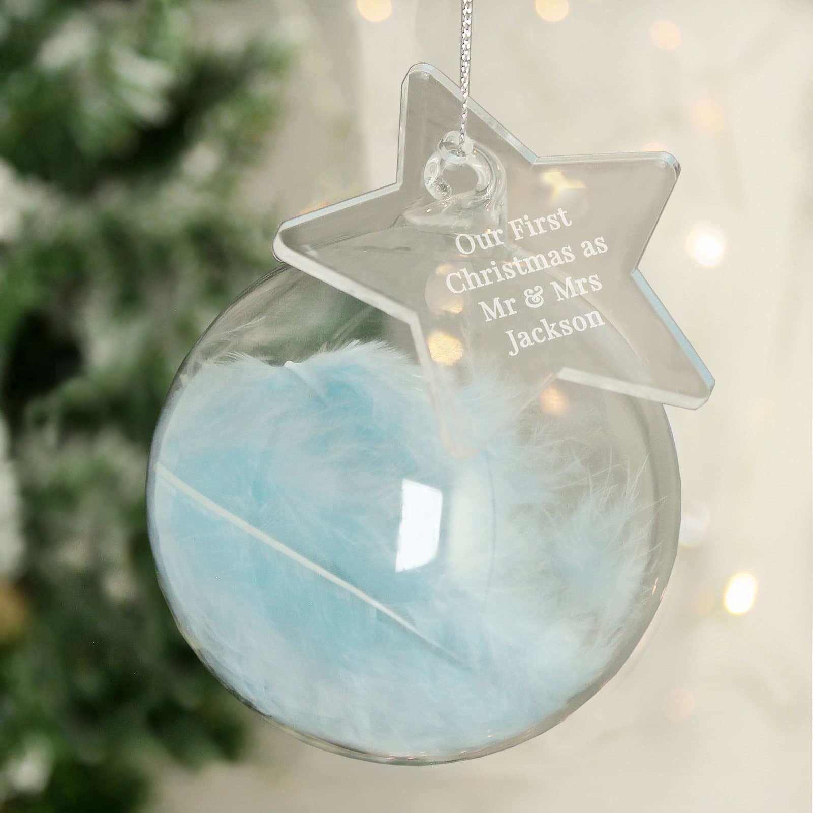 Glass bauble filled with a blue feather and an acrylic star tag