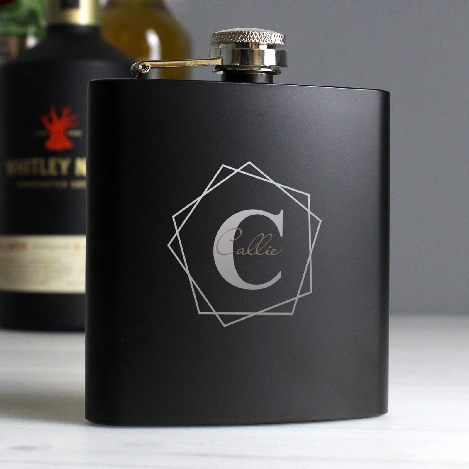 Black stainless steel hip flask with a geometric two-tone engraved initial and name