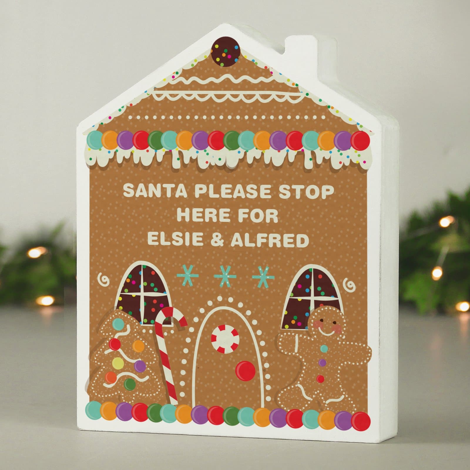 Free-standing wooden gingerbread house ornament with a message in the centre