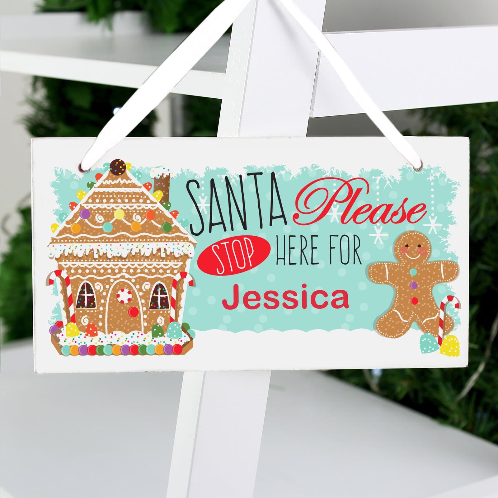 Wooden gingerbread house sign reading Santa Please Stop Here For with a ribbon