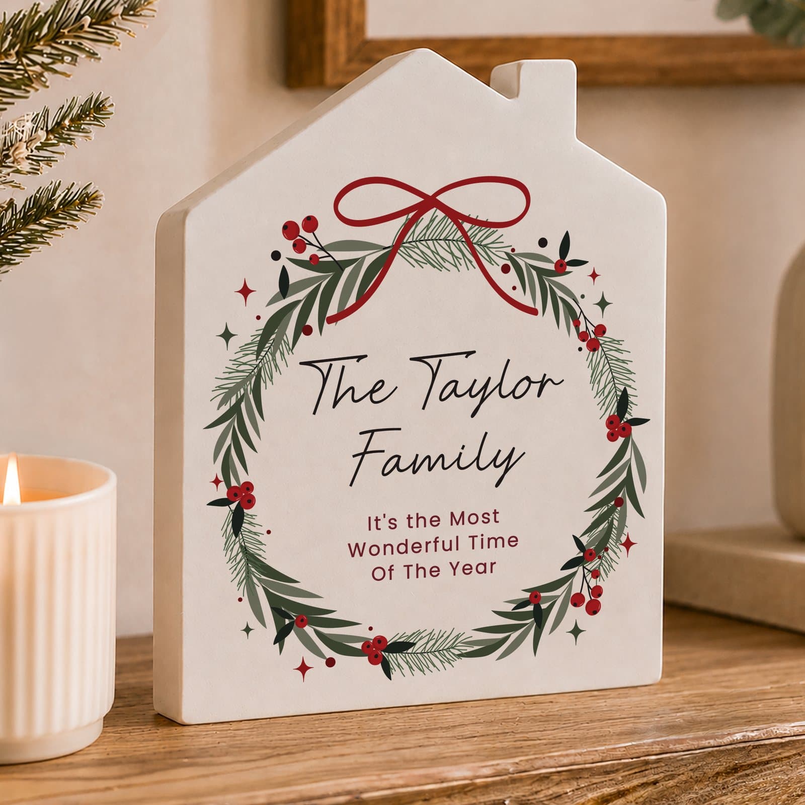 Wooden house ornament with a green Christmas wreath and personalised text