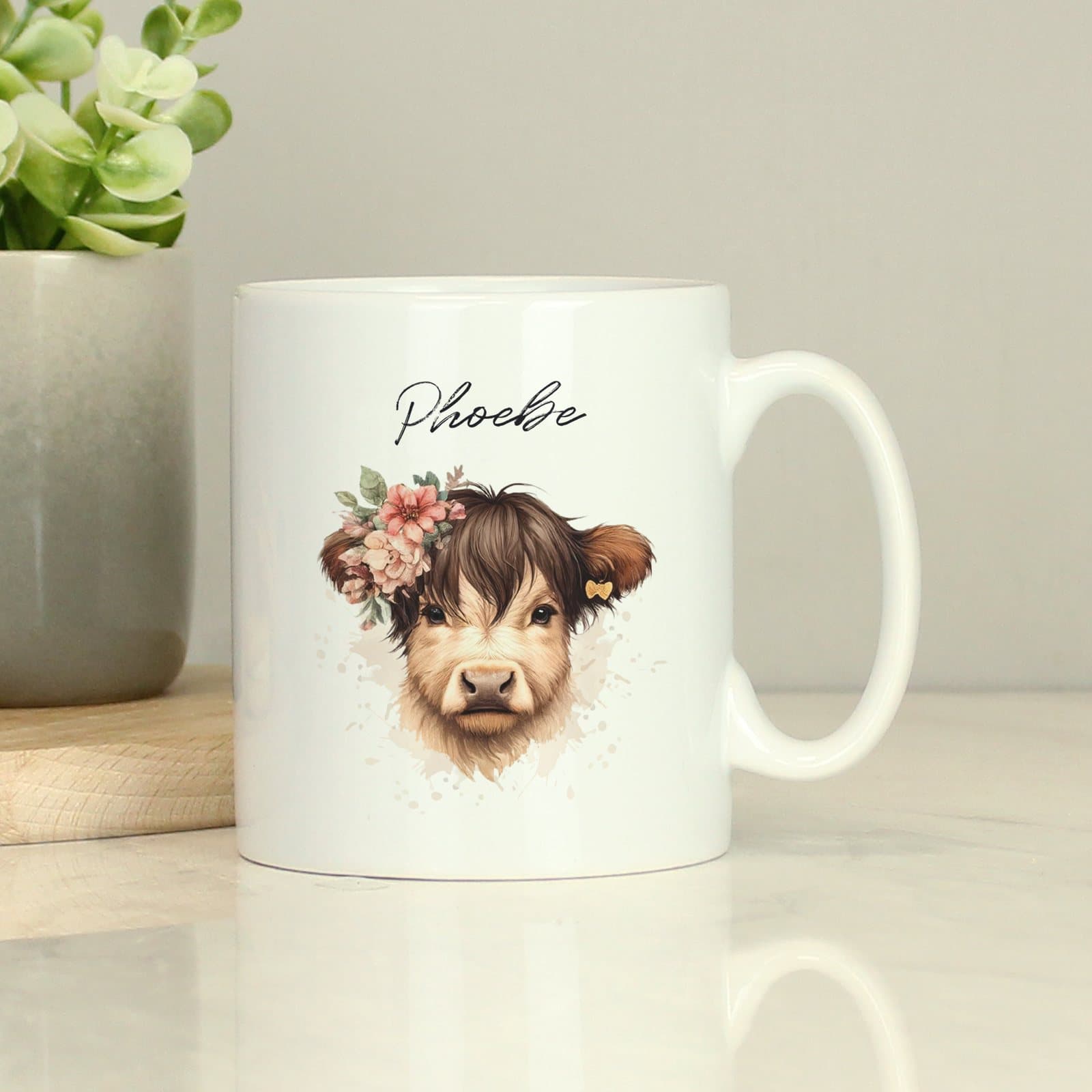 Personalised ceramic mug with a Highland cow design and a name above it