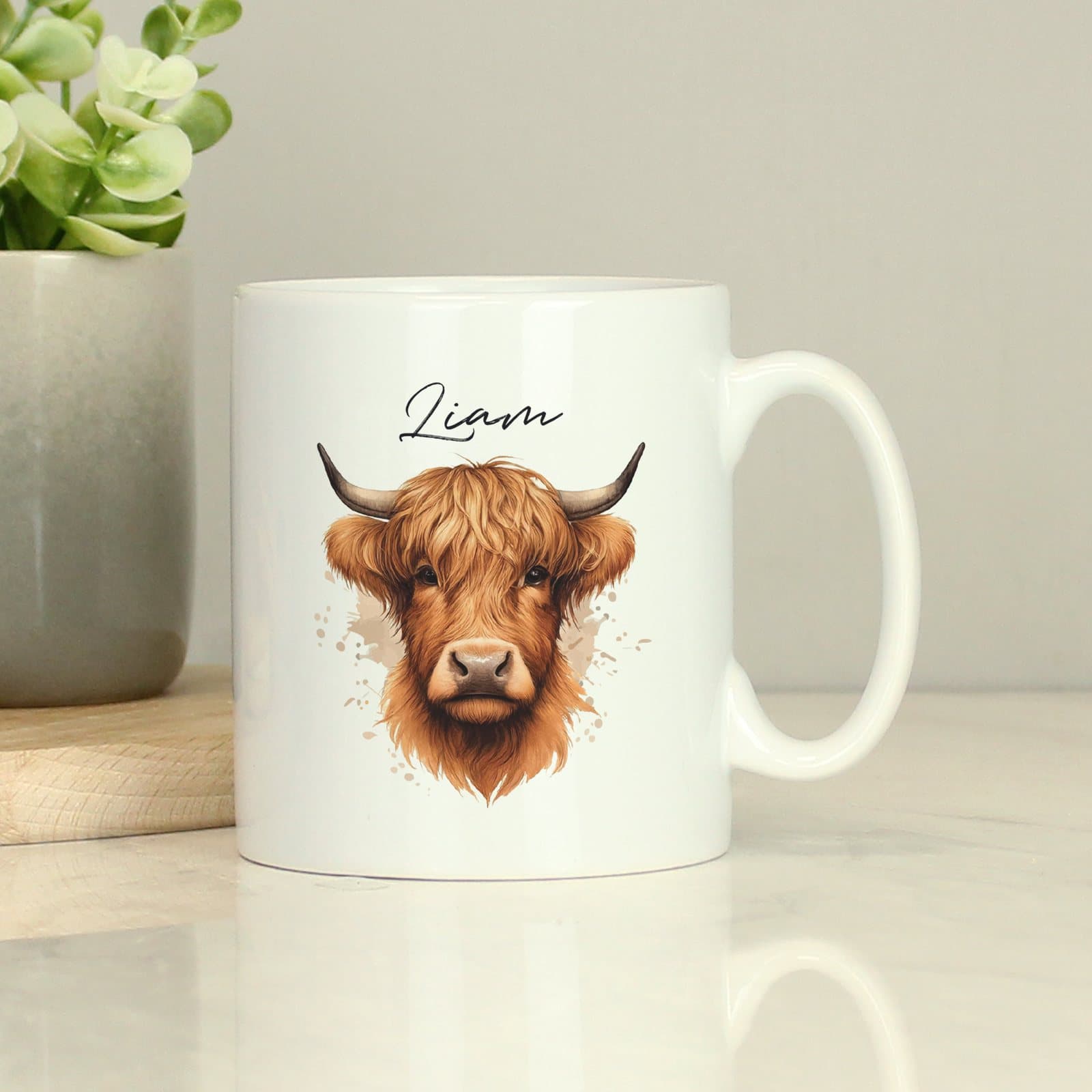 Personalised ceramic mug with a Highland cow design and a name above it