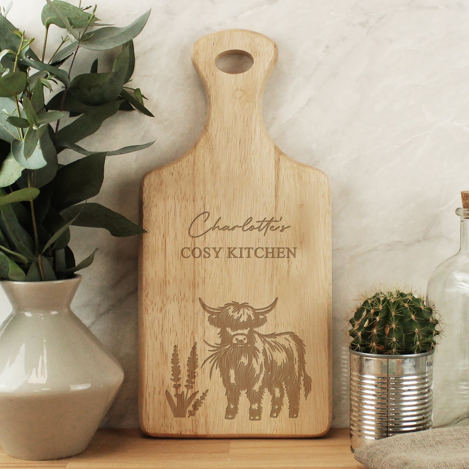 Wooden paddle chopping board with a Highland cow design and two lines of text