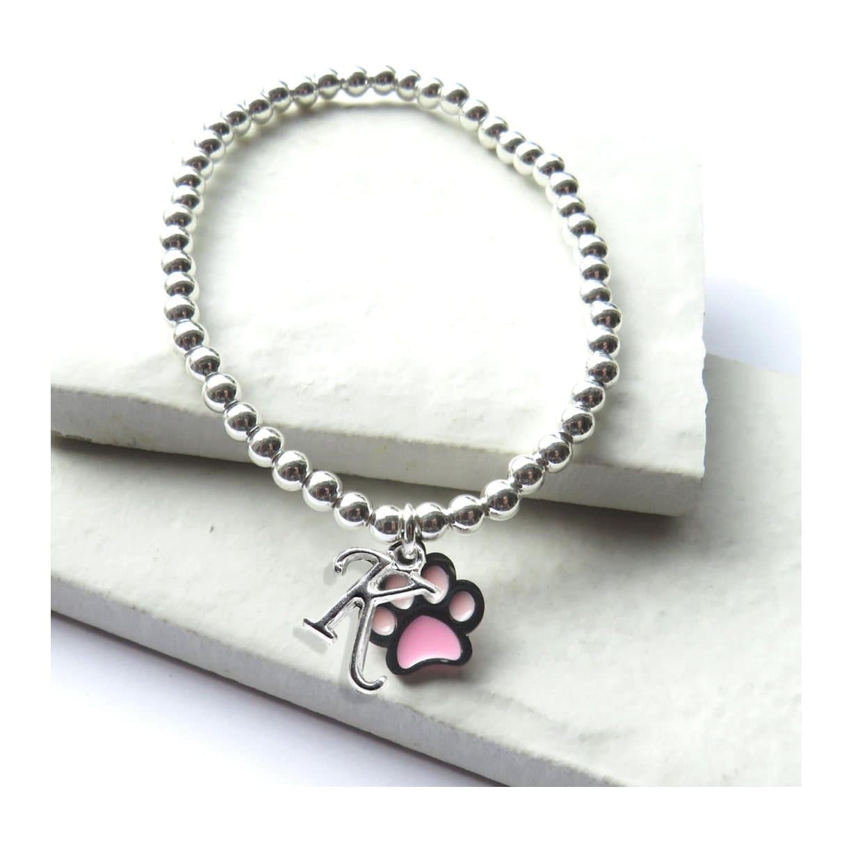 Silver beaded stretch bracelet with a pink paw charm and a silver plated initial