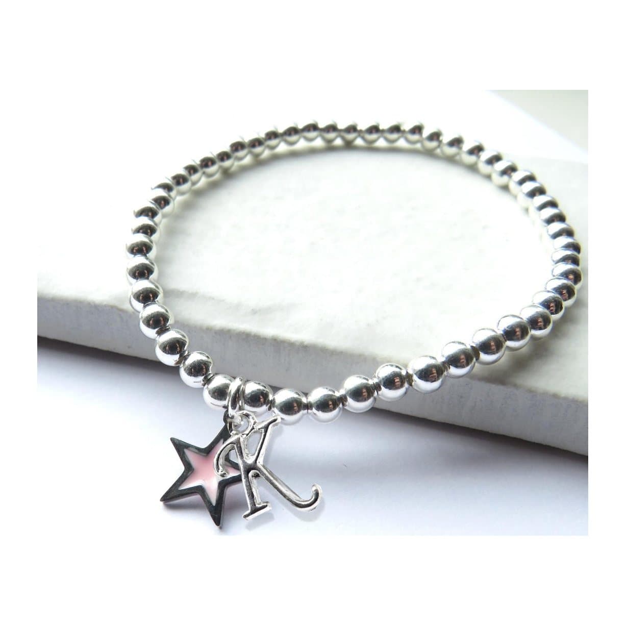 Silver beaded stretch bracelet with a silver initial charm and a pink enamel star