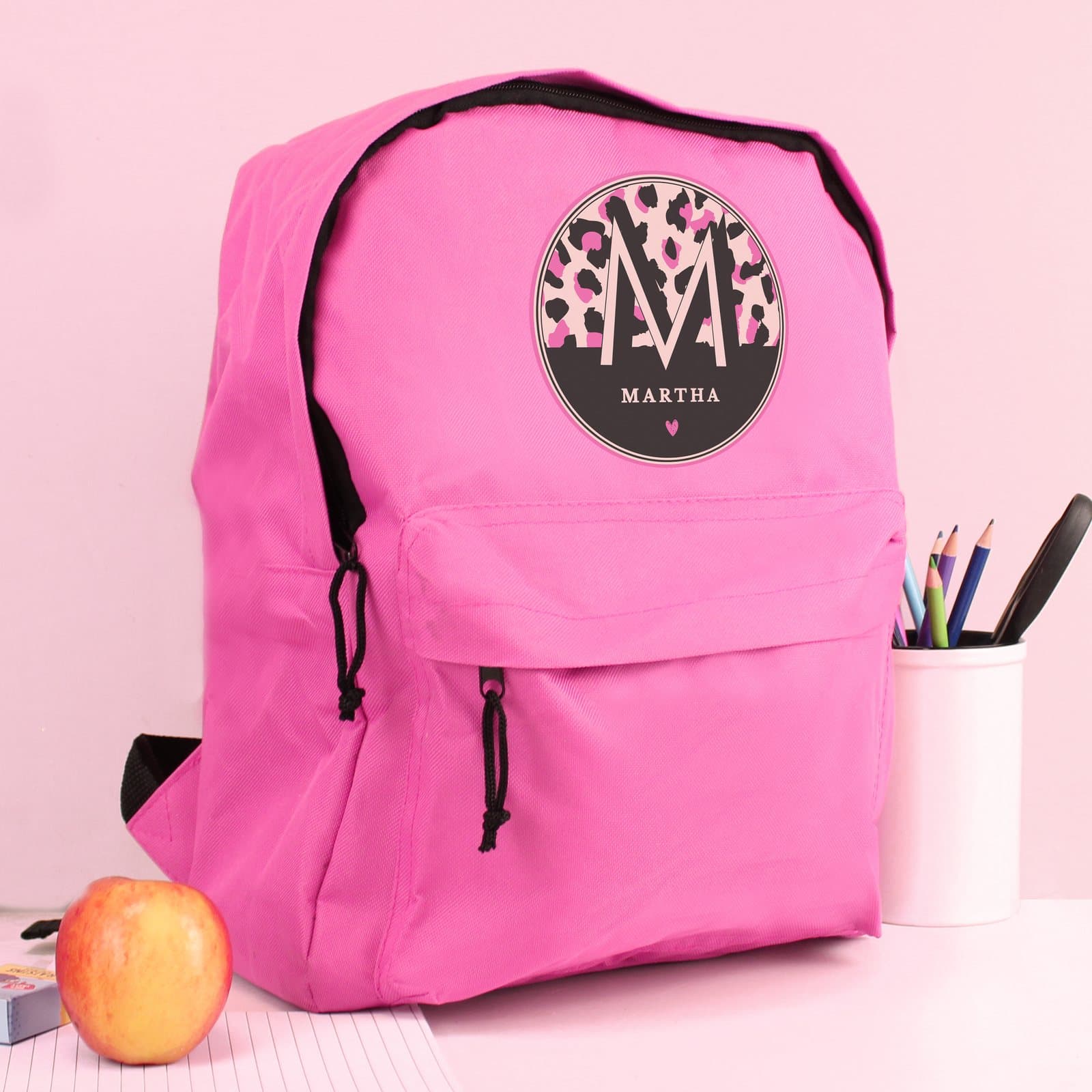 Pink backpack in leopard print with padded straps and a front zip pocket