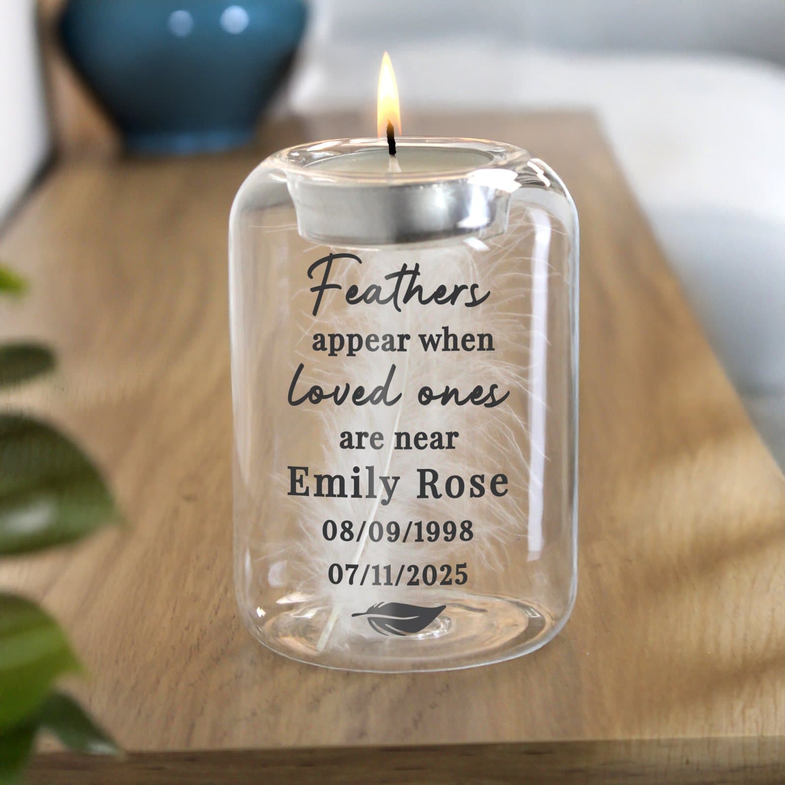 Glass tealight holder containing a white feather with personalised text