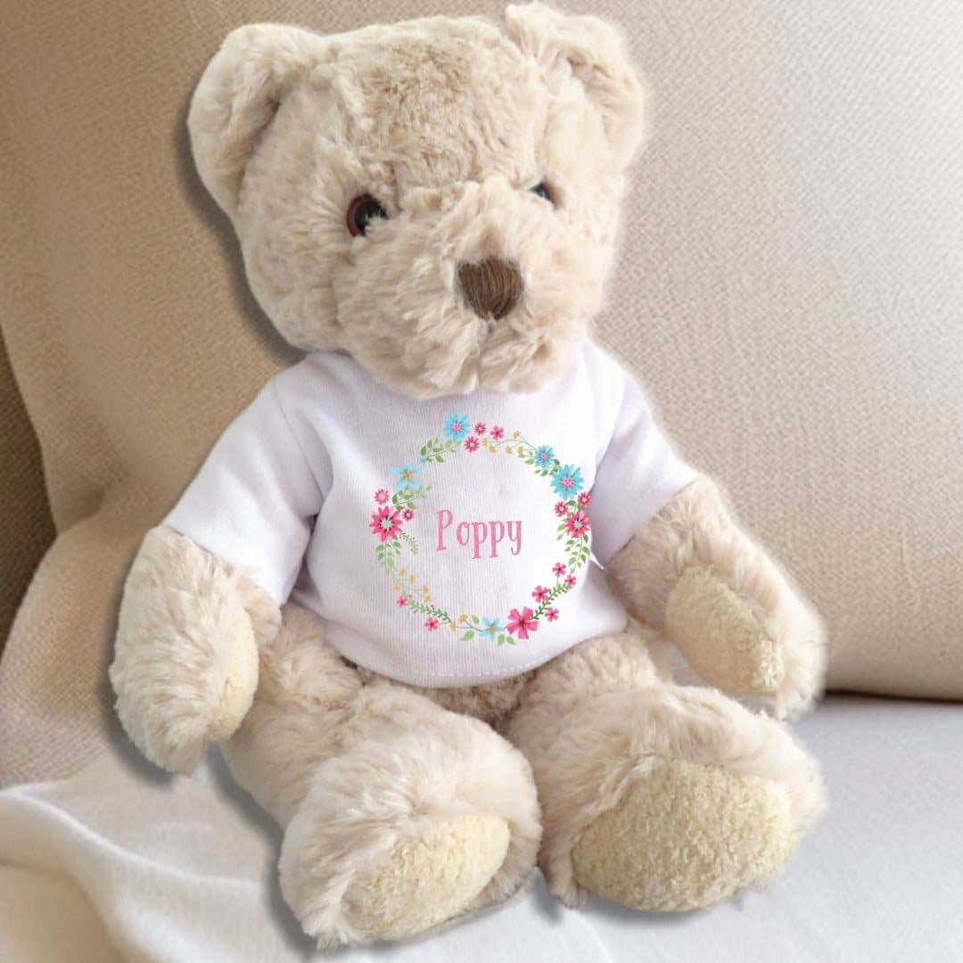 Teddy bear wearing a pink floral T-shirt with pink, blue and yellow blooms