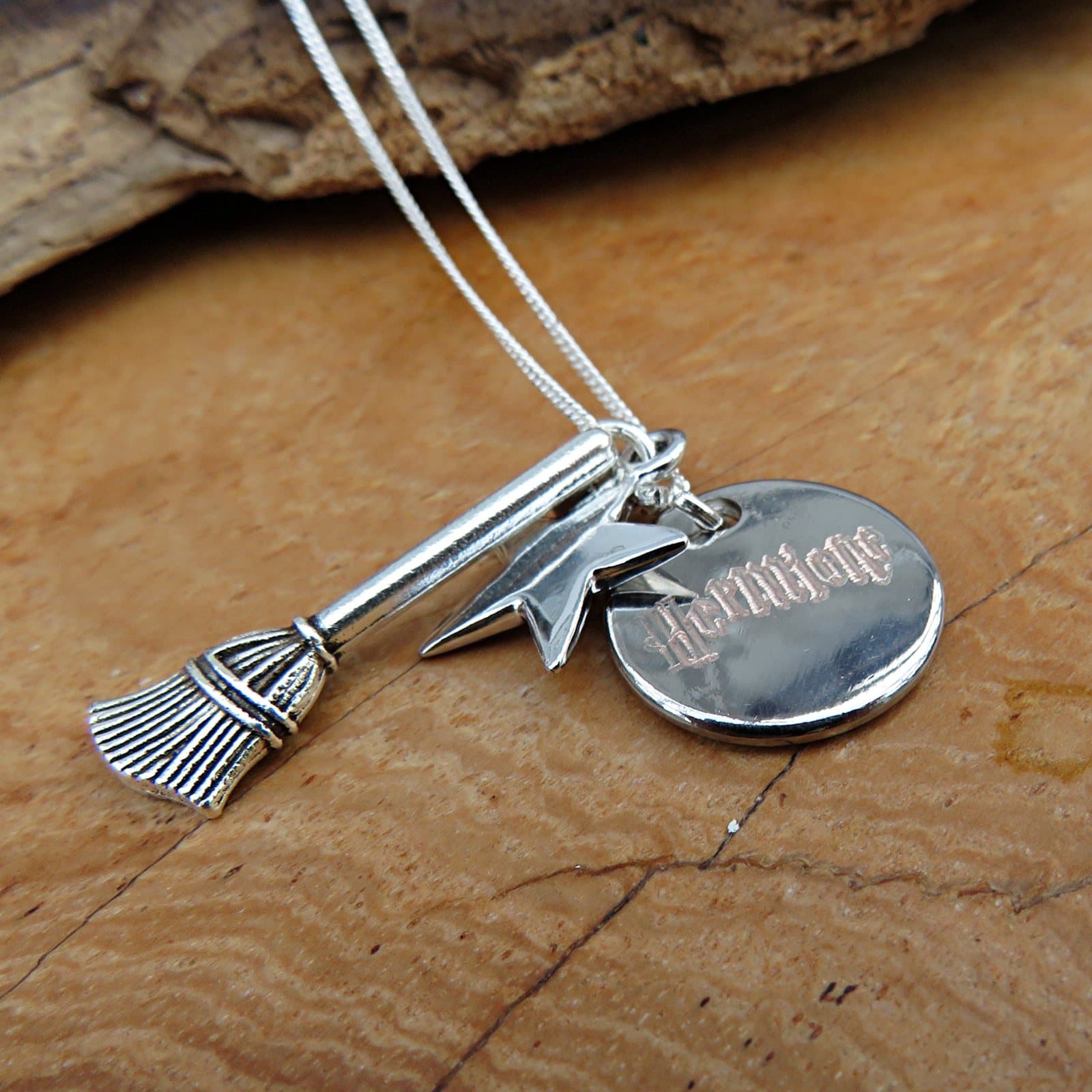 Silver broom and star charm on a chain, with a round engraved disc