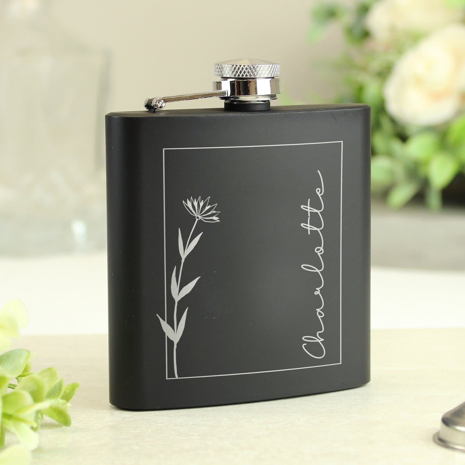 Black stainless steel hip flask with a monochrome floral design and a name