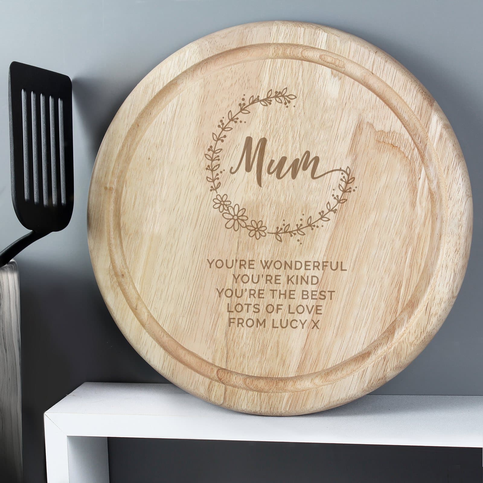 Round natural wood chopping board engraved with the word Mum and lines of text