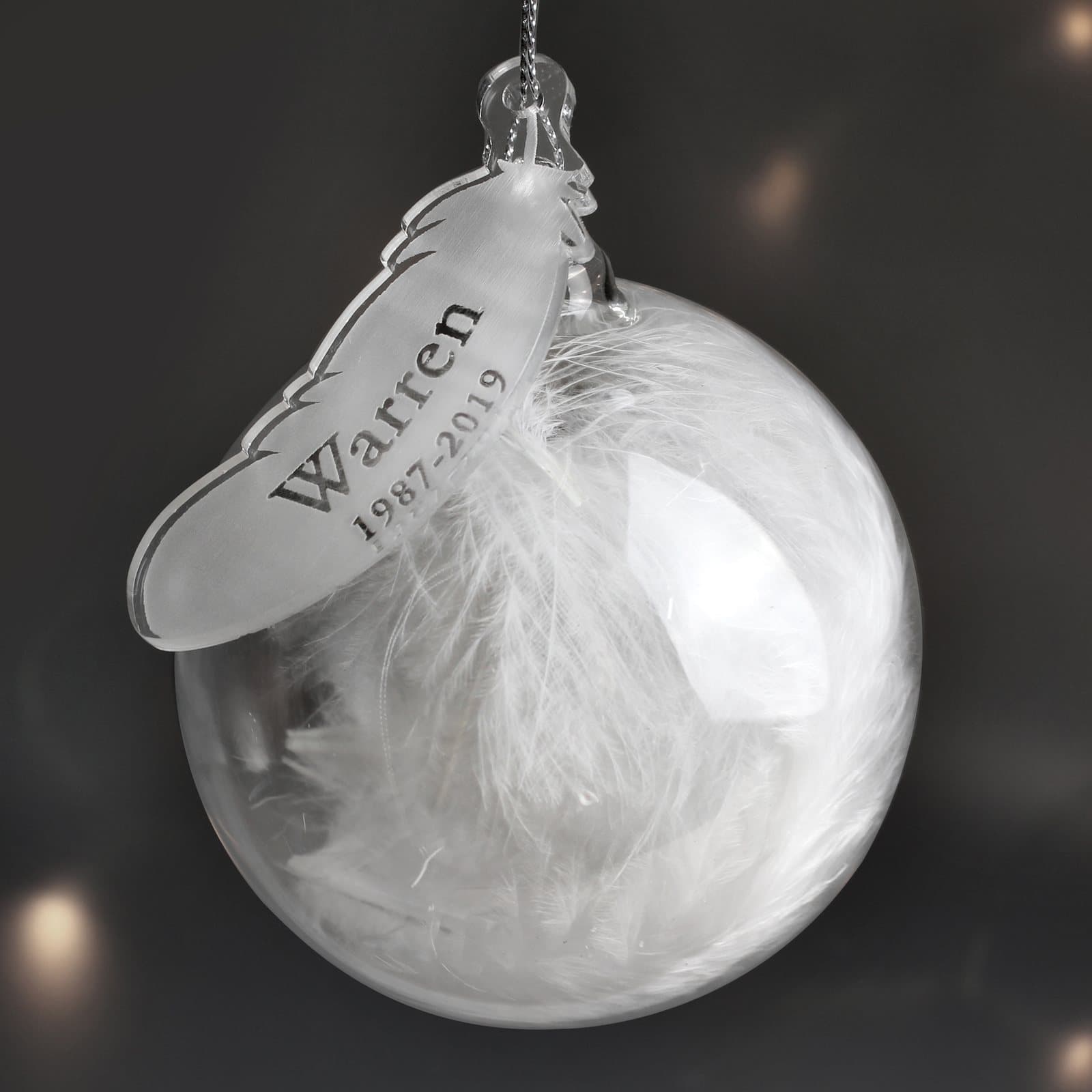 Glass bauble filled with a feather and an acrylic feather tag
