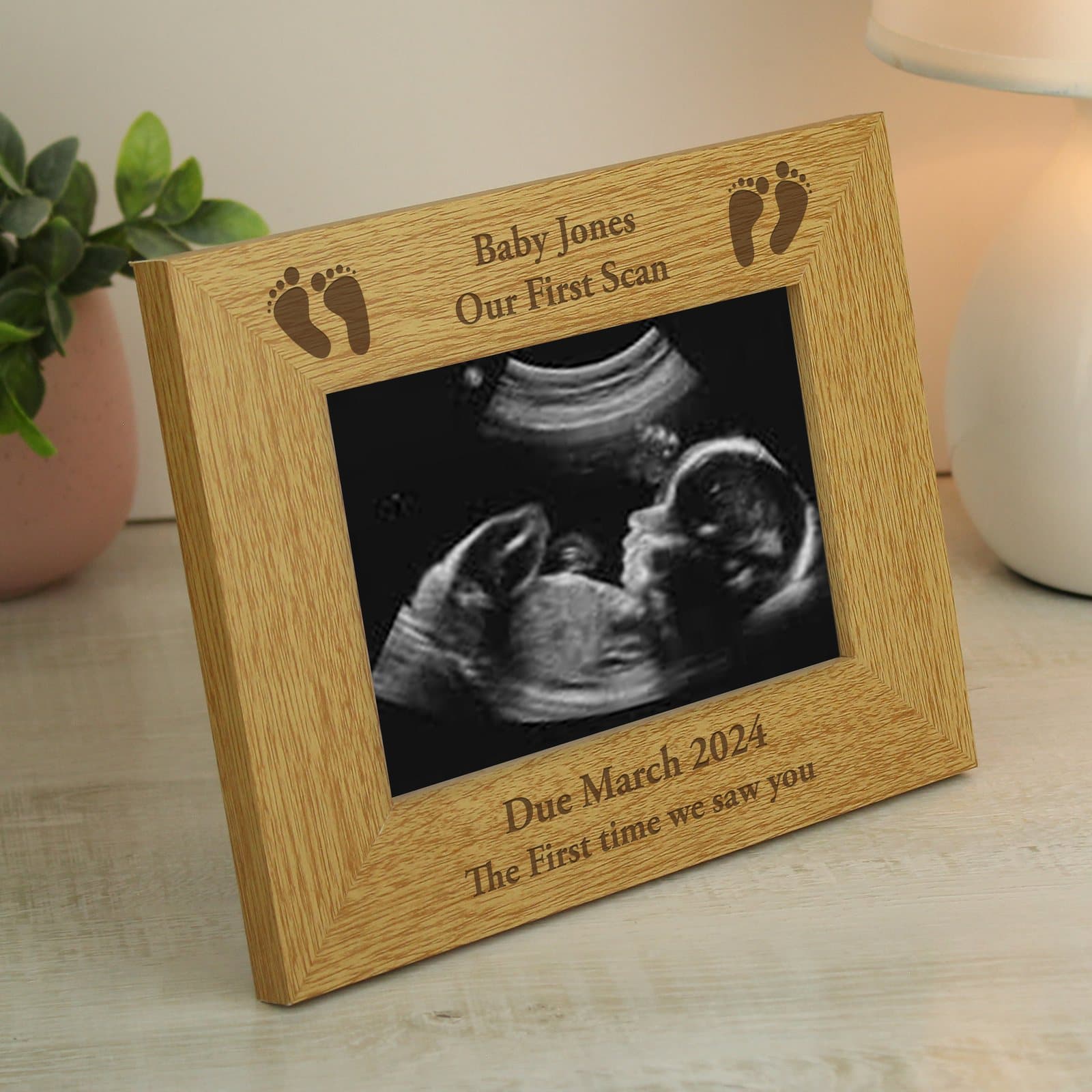 Oak finish baby footprints photo frame with a foot design and text above and below