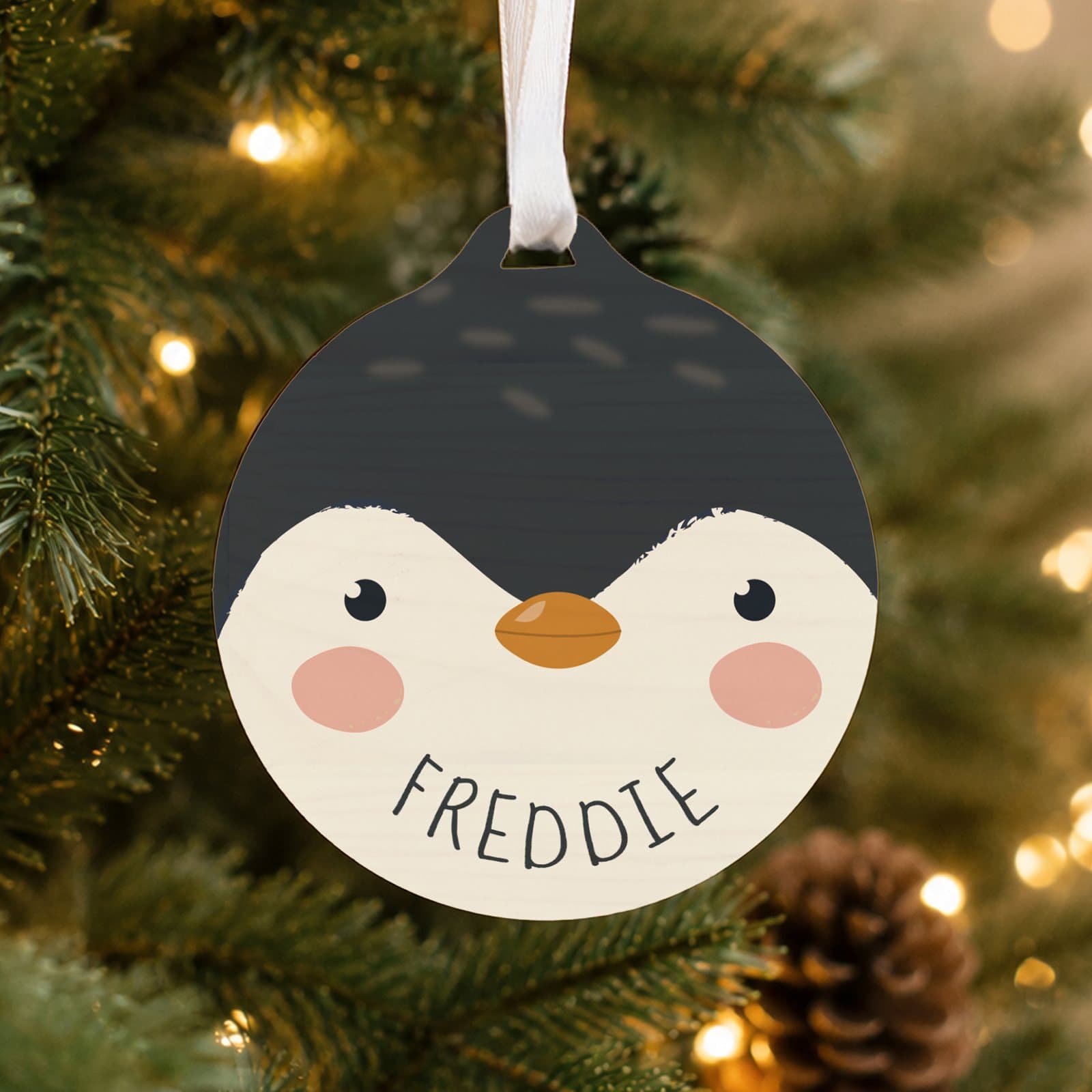 Round wooden bauble with a cartoon penguin design and ribbon