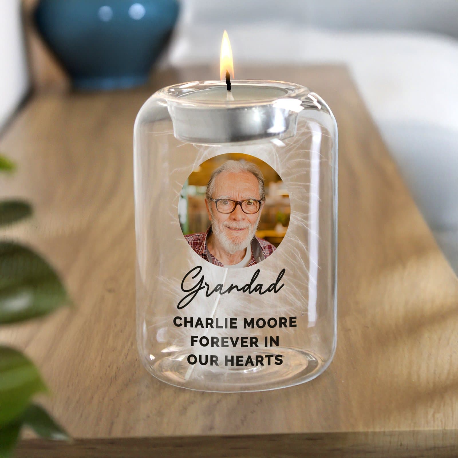Glass tealight holder with a white feather inside and a photo