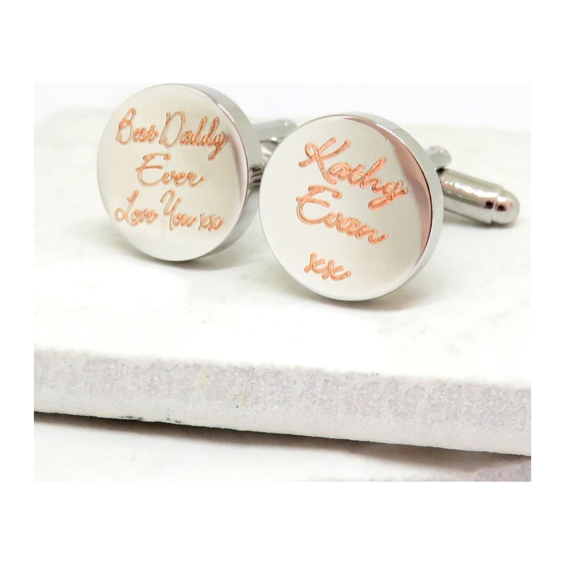 Round silver-coloured cufflinks with a handwritten script name engraved on them