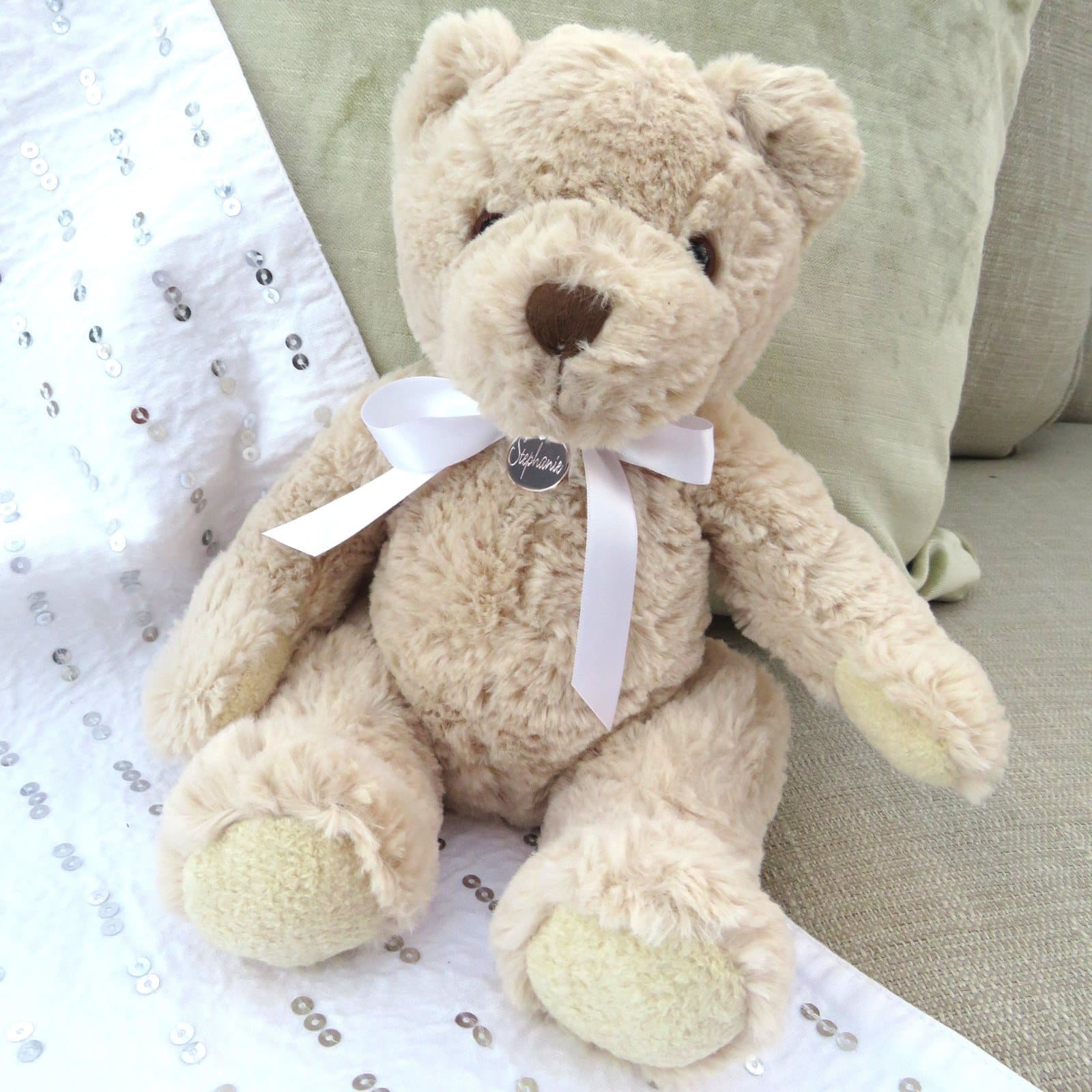 Teddy bear with a name engraved on a stainless steel disc on a white satin ribbon