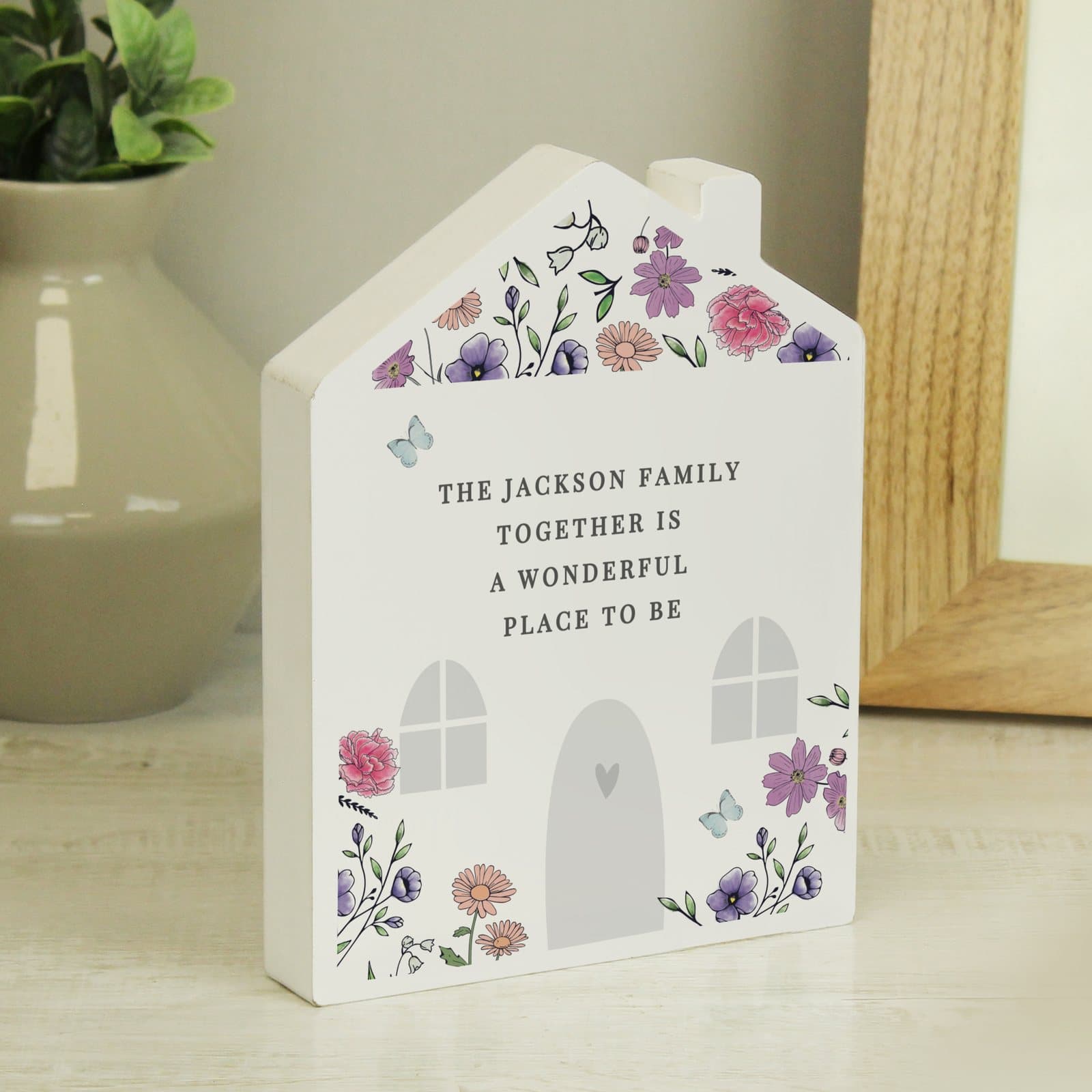 Free-standing wooden house ornament with wildflower illustrations on the front