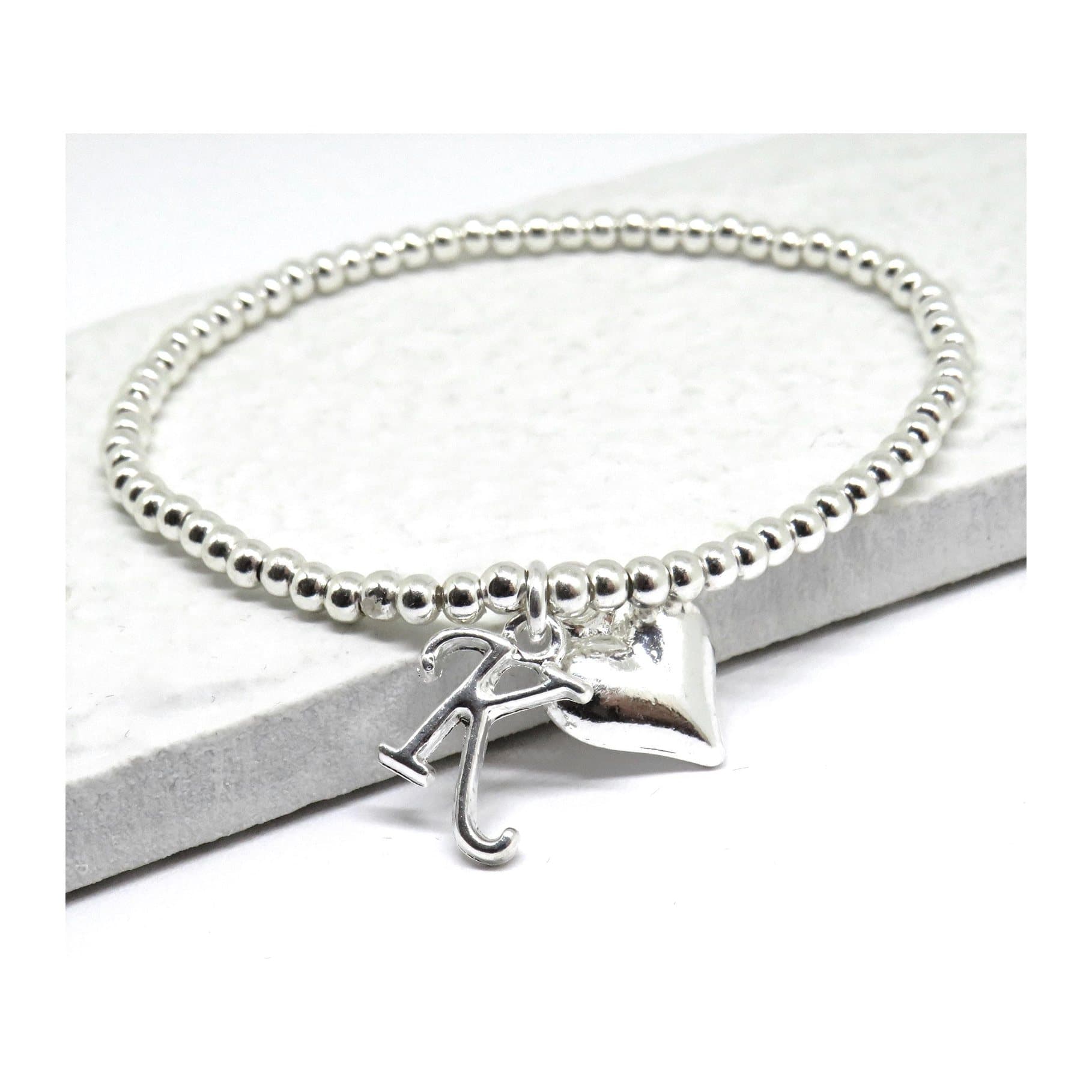 Silver beaded stretch bracelet with a heart charm and an initial charm