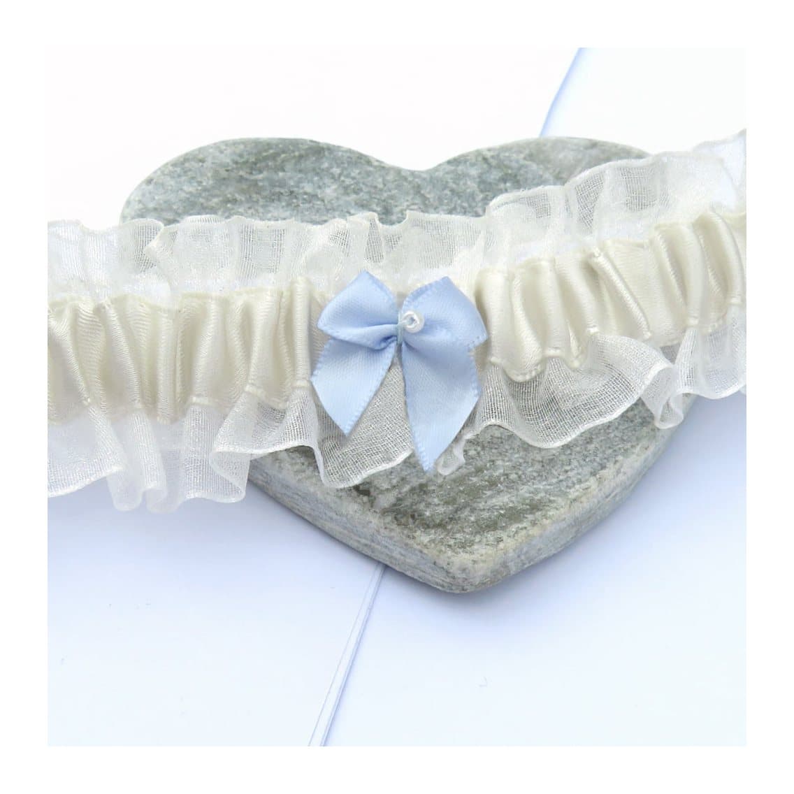 Pale ivory wedding garter with a blue bow and small pearl in the centre