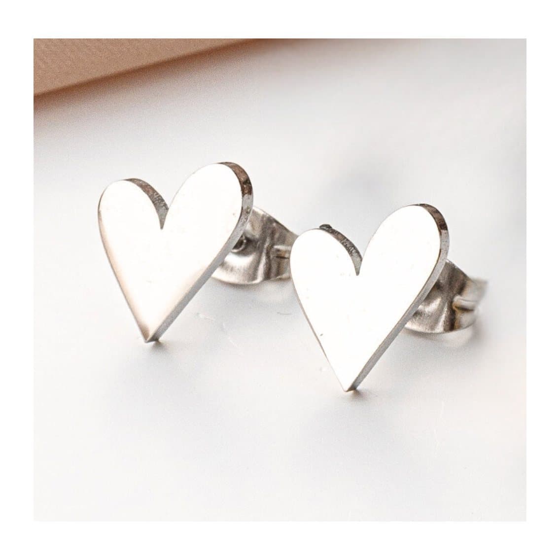 Tilted heart stud earrings in stainless steel, with a heart design